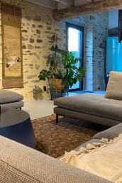 A big lounge couch with hocker, flatscreen TV, and a persian rug.